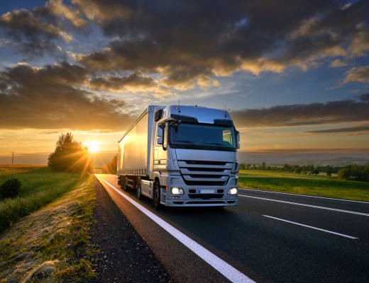 Truck driving on the asphalt road in rural landscape at sunset with dark clouds Truck driving on the asphalt road in rural landscape at sunset with dark clouds